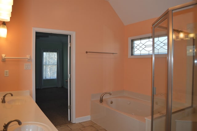 bathroom featuring tile patterned flooring, lofted ceiling, a garden tub, and a sink