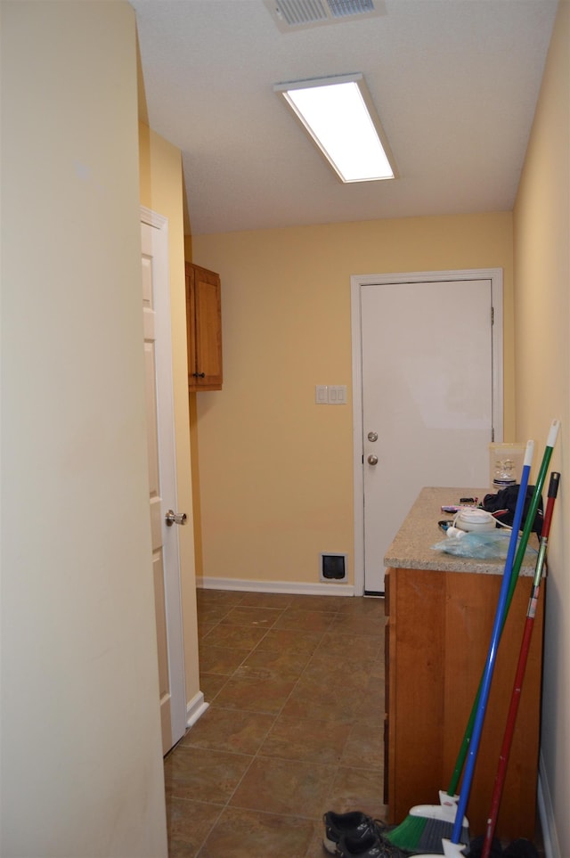 hall with dark tile patterned flooring, baseboards, and visible vents