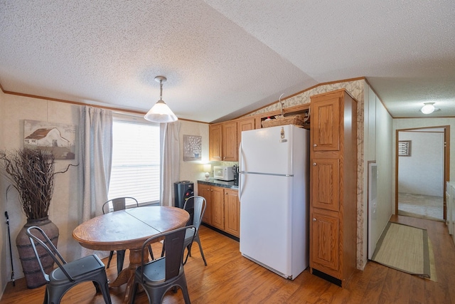 kitchen featuring visible vents, ornamental molding, white appliances, light wood finished floors, and vaulted ceiling