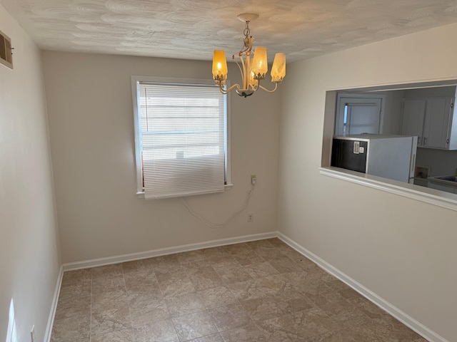 empty room with baseboards and an inviting chandelier