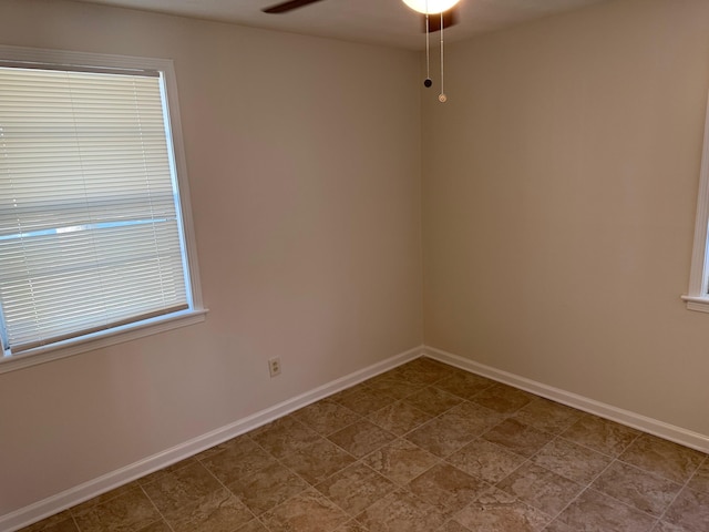 empty room featuring ceiling fan and baseboards