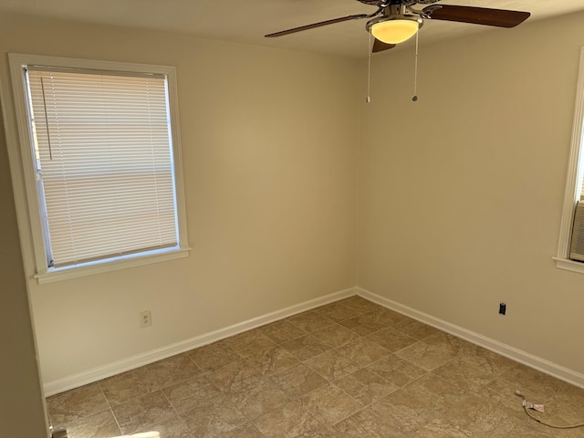 empty room with ceiling fan and baseboards