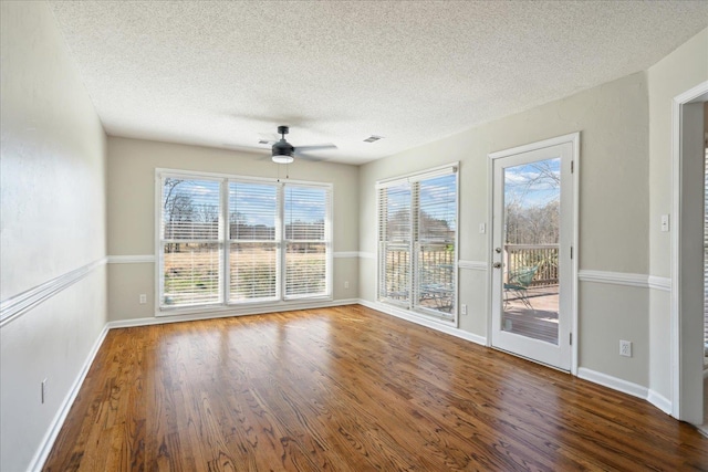 empty room with baseboards, a textured ceiling, ceiling fan, and wood finished floors