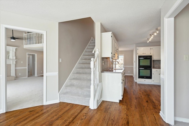 stairway featuring a textured ceiling, baseboards, and wood finished floors