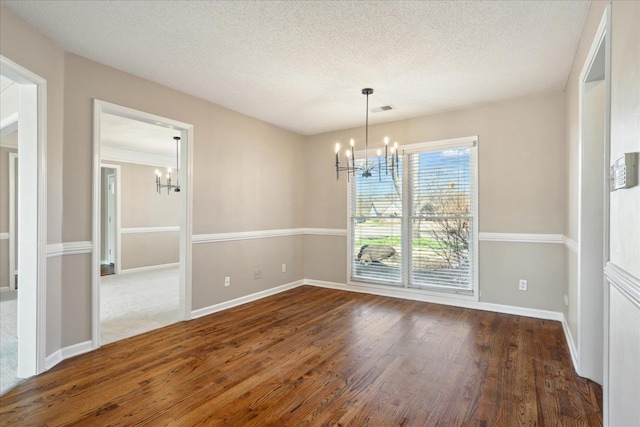 unfurnished dining area with visible vents, a notable chandelier, wood finished floors, and a textured ceiling