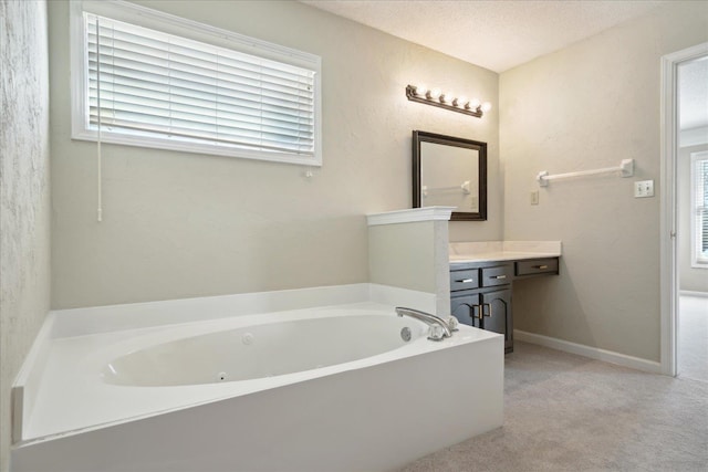 bathroom featuring baseboards, a textured ceiling, a jetted tub, and vanity