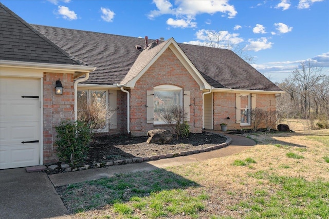 ranch-style home featuring a garage, brick siding, and roof with shingles