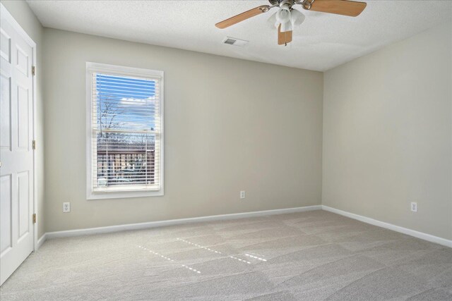 carpeted empty room featuring visible vents, baseboards, a textured ceiling, and a ceiling fan