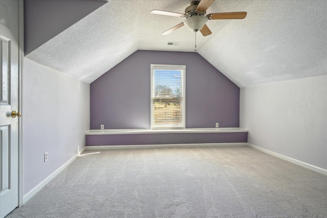 bonus room with visible vents, a textured ceiling, carpet flooring, and vaulted ceiling