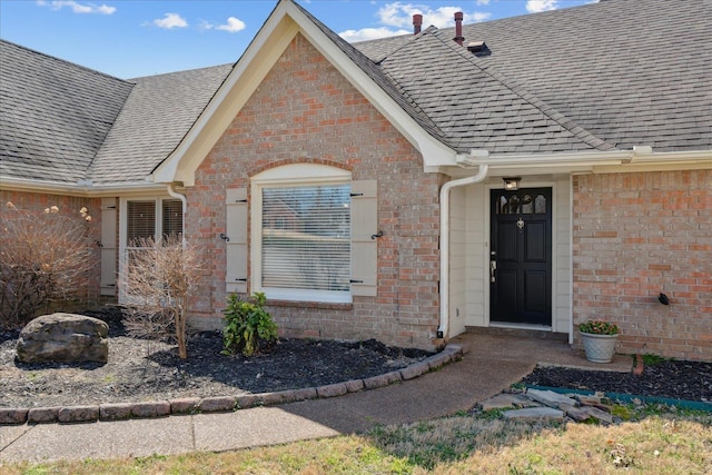 entrance to property with brick siding and roof with shingles