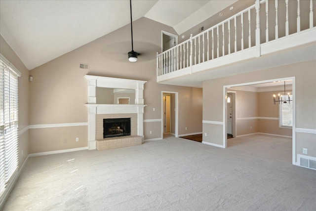 unfurnished living room featuring visible vents, carpet, a fireplace, and ceiling fan with notable chandelier