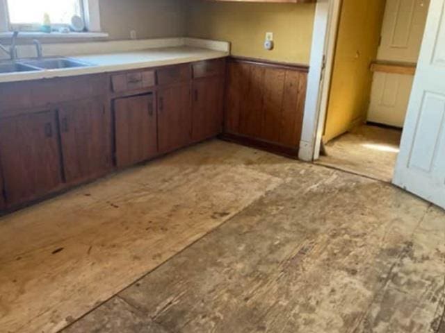 kitchen with a sink, wooden walls, and wainscoting