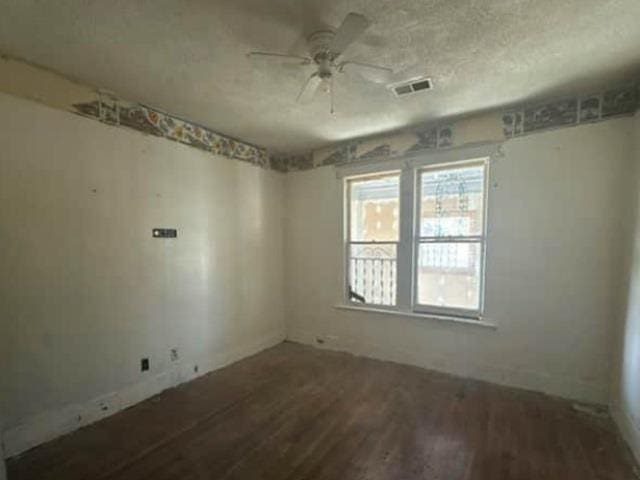 unfurnished room featuring visible vents, a textured ceiling, a ceiling fan, and wood finished floors