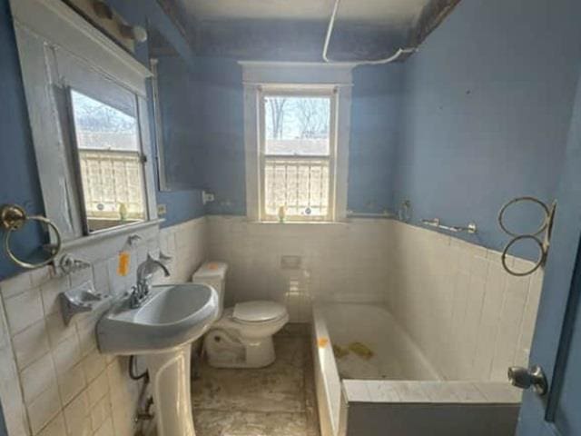 full bath featuring toilet, tile walls, wainscoting, a bathtub, and walk in shower