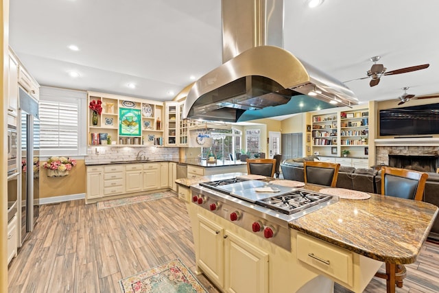 kitchen featuring dark stone counters, recessed lighting, light wood-style floors, appliances with stainless steel finishes, and island range hood