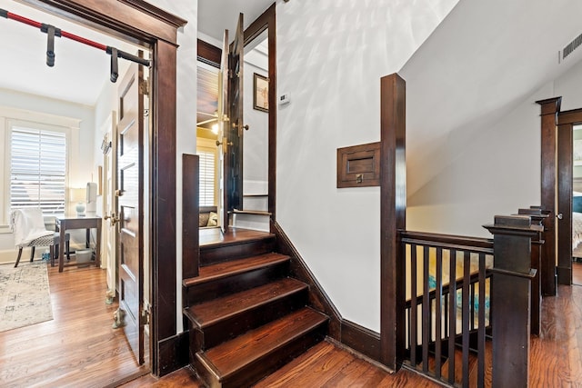 stairway featuring a healthy amount of sunlight and wood finished floors