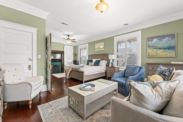 bedroom with visible vents, ornamental molding, a fireplace, and wood finished floors