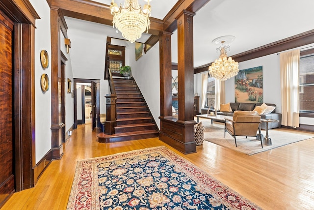 foyer with ornate columns, plenty of natural light, stairs, and an inviting chandelier