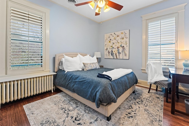 bedroom with visible vents, a ceiling fan, wood finished floors, radiator heating unit, and crown molding