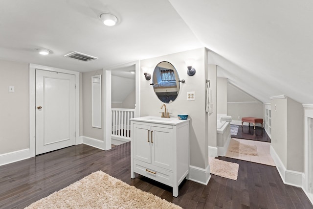 corridor featuring visible vents, dark wood-type flooring, lofted ceiling, a sink, and baseboards