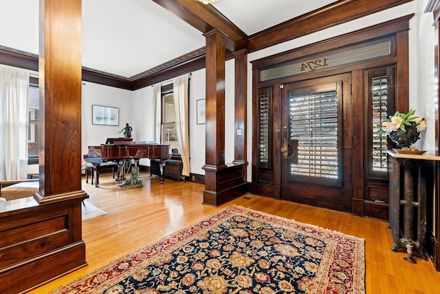 entrance foyer with wood finished floors, crown molding, and decorative columns