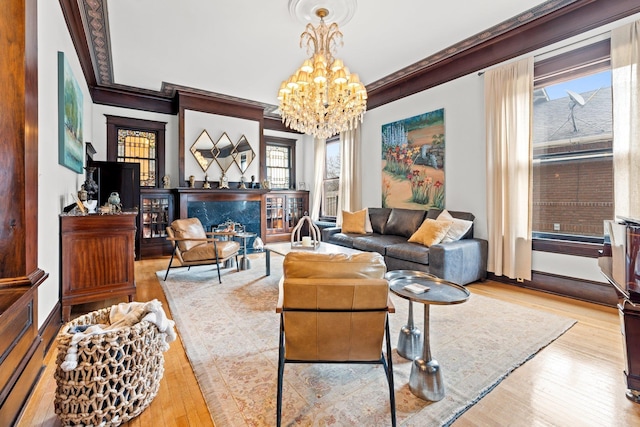 living area with a fireplace, a notable chandelier, wood finished floors, and ornamental molding