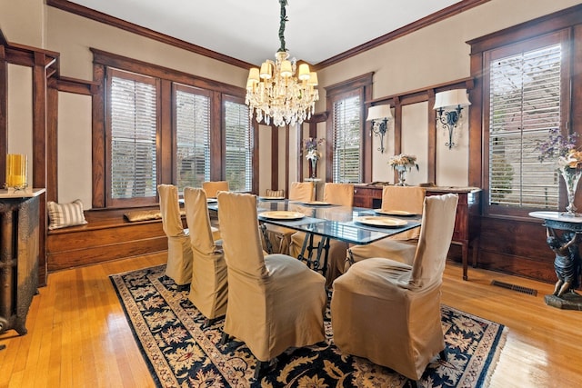 dining space featuring a notable chandelier, crown molding, visible vents, and wood-type flooring