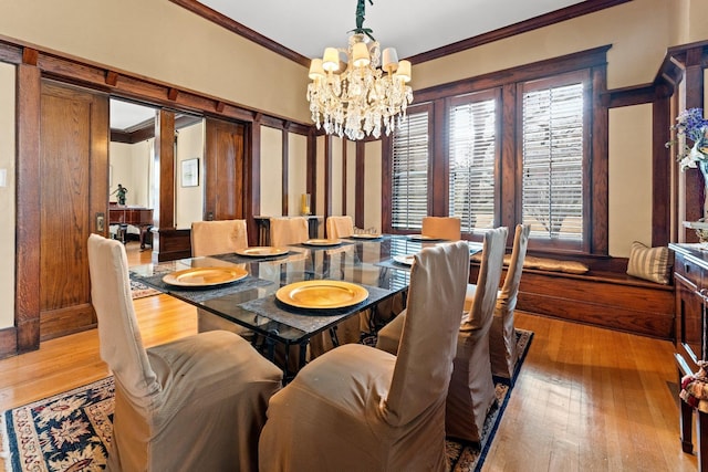 dining area with hardwood / wood-style floors, a notable chandelier, and ornamental molding