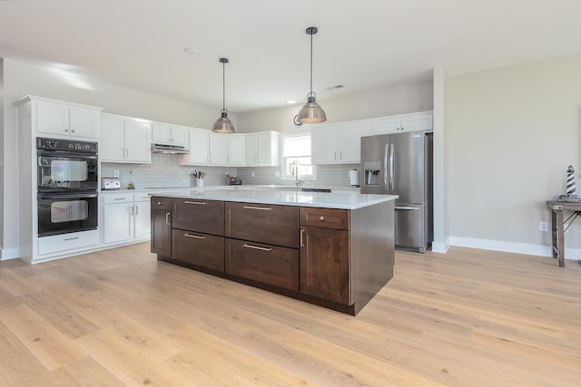 kitchen with stainless steel fridge with ice dispenser, light countertops, white cabinets, under cabinet range hood, and dobule oven black