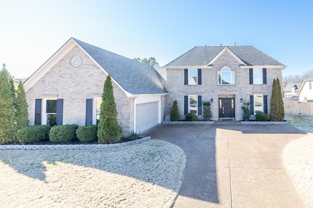 colonial-style house with a garage, brick siding, driveway, and fence