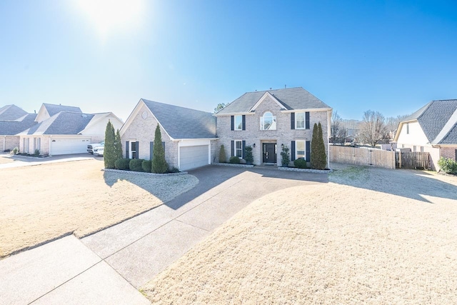 colonial house featuring fence, a residential view, concrete driveway, an attached garage, and a gate