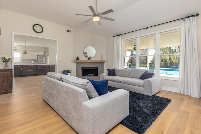 living room with a fireplace, plenty of natural light, a ceiling fan, and light wood finished floors