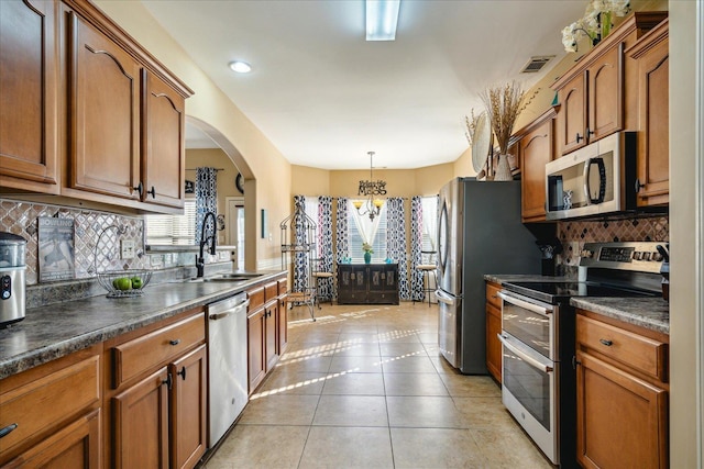 kitchen featuring dark countertops, a wealth of natural light, light tile patterned floors, and appliances with stainless steel finishes