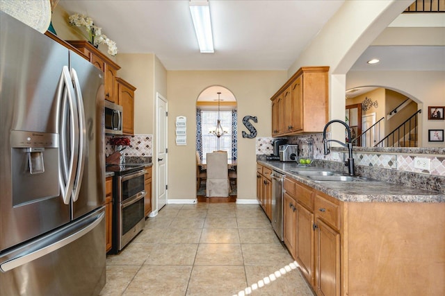 kitchen with a sink, stainless steel appliances, arched walkways, and light tile patterned floors