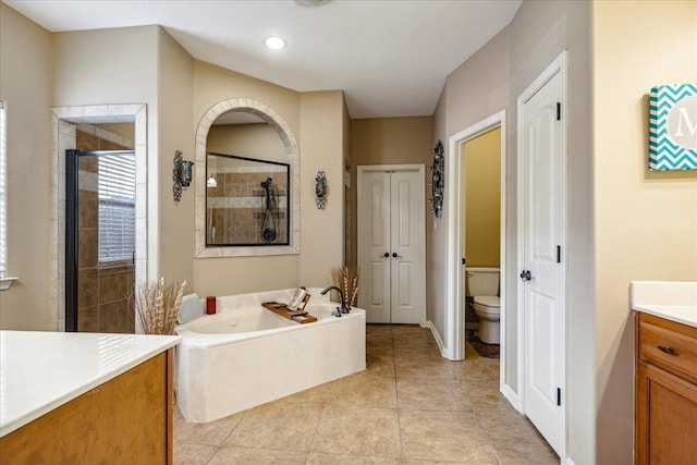 bathroom featuring vanity, a stall shower, tile patterned flooring, a garden tub, and toilet