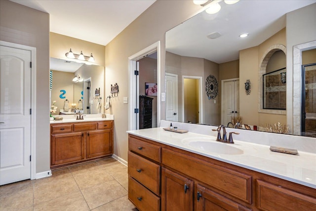 bathroom with tile patterned floors, tiled shower, two vanities, and a sink