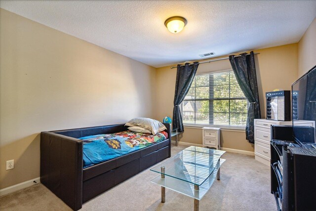 bedroom with a textured ceiling, baseboards, visible vents, and light carpet