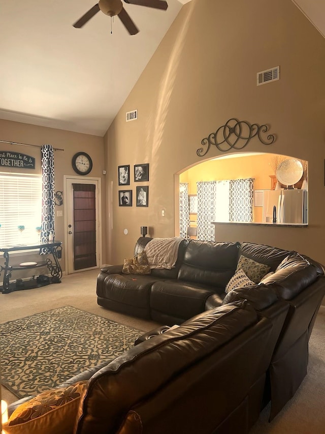 carpeted living room with visible vents, high vaulted ceiling, and a ceiling fan