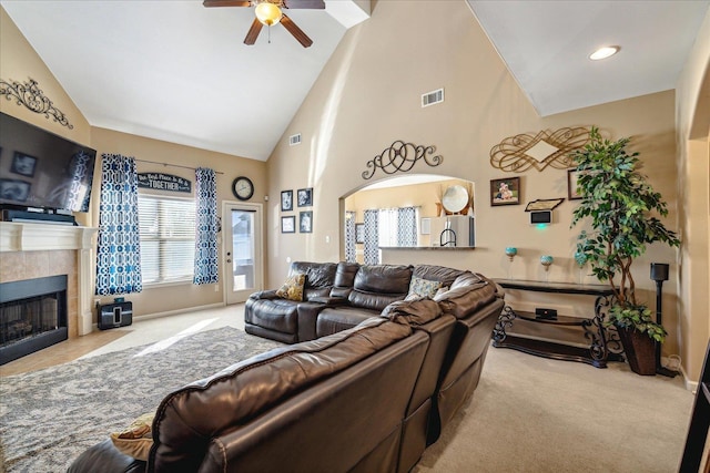 living area featuring high vaulted ceiling, a fireplace, visible vents, and light carpet