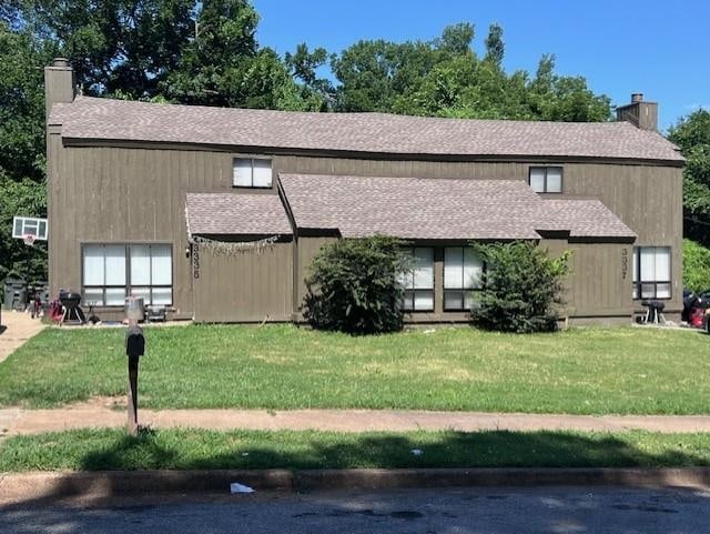 view of front of house with a chimney, a front lawn, and a shingled roof