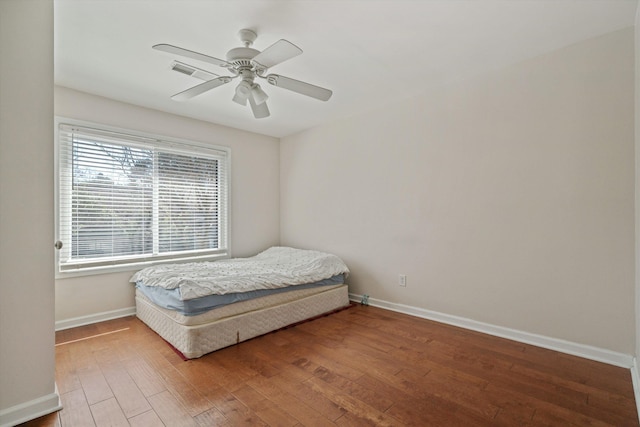 bedroom with a ceiling fan, wood finished floors, and baseboards