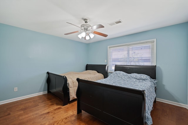 bedroom featuring ceiling fan, visible vents, baseboards, and wood finished floors