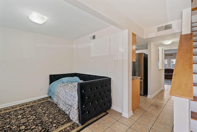 bedroom with light tile patterned floors, baseboards, visible vents, and freestanding refrigerator