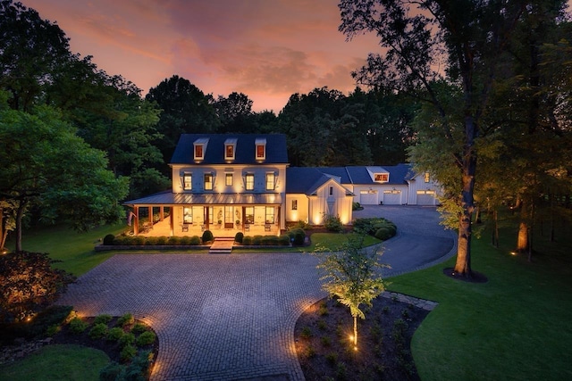 view of front of house featuring decorative driveway, a lawn, and covered porch