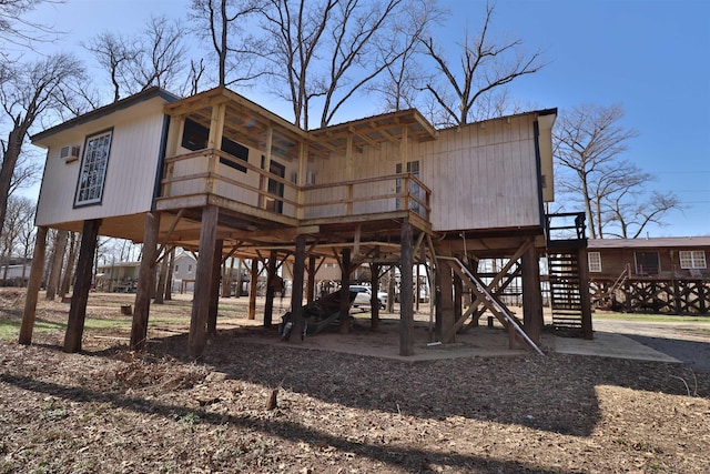 rear view of property with stairway, a carport, a deck, and dirt driveway