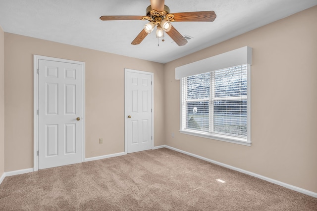 unfurnished bedroom with a ceiling fan, carpet flooring, visible vents, and baseboards