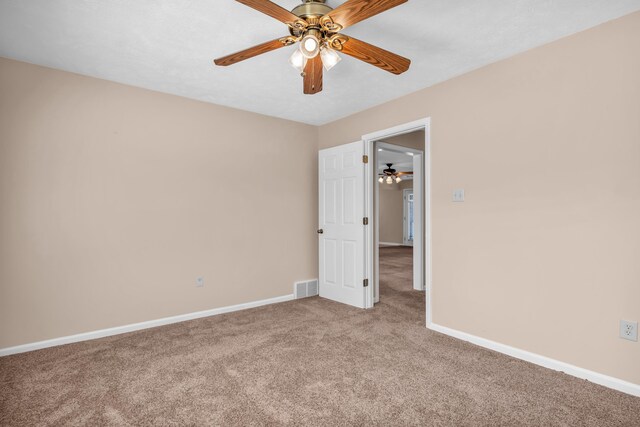 empty room with visible vents, light colored carpet, baseboards, and ceiling fan