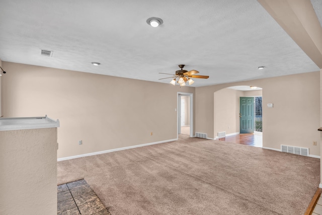 unfurnished living room featuring visible vents, arched walkways, and carpet flooring