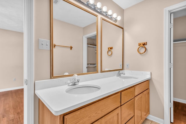 full bathroom with a sink, baseboards, and double vanity