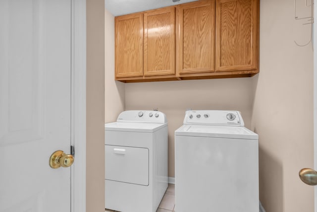 washroom featuring light tile patterned floors, cabinet space, and washing machine and dryer